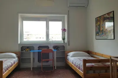 a room with two beds and a desk with a window at Casa Marconi apt in Rome