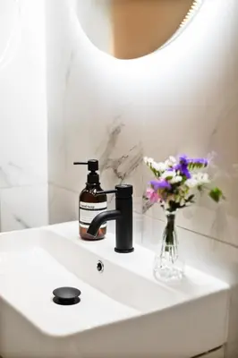 a bathroom sink with a bottle of soap and a vase of flowers at Volturno Boutique Apartment in Rome