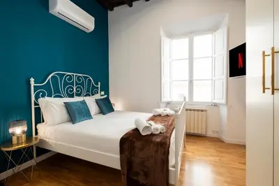 a bedroom with a white bed with blue walls at Domus Maggiore Apartment in Rome
