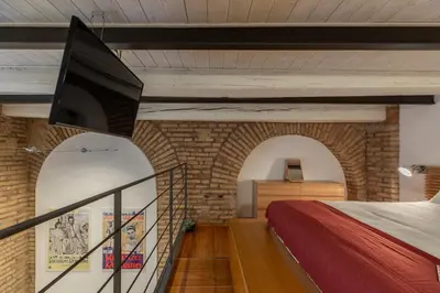 a room with a bed and a tv on a brick wall at iFlat Cozy & Serene Loft Two Steps from Vatican in Rome