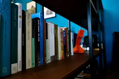 a row of books sitting on a book shelf at Gioia House in Rome
