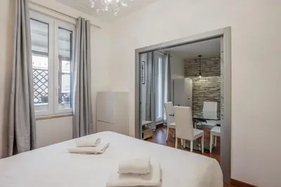 a white bedroom with a bed and a dining room at Maison Riboty - by 101Flats in Rome
