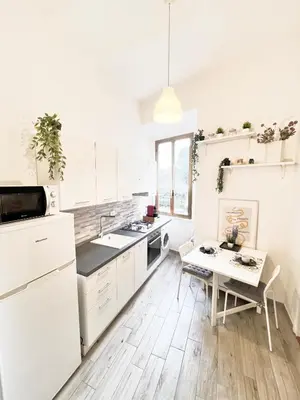 a kitchen with white cabinets and a small table at FlowflatPigneto in Rome