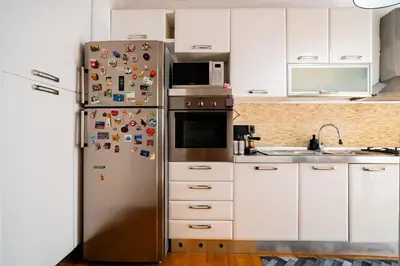a kitchen with a stainless steel refrigerator covered in magnets at Vatican Blossom in Rome