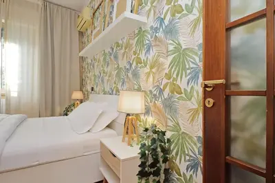 a bedroom with a bed and a tropical wallpaper at Lucky Domus Tuscolano in Rome