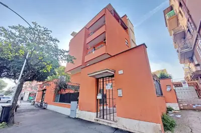 an orange building on the side of a street at Lucky Domus Tuscolano in Rome
