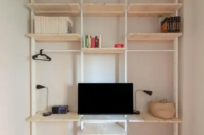 a tv sitting on a desk in a room with shelves at Modern Spacious Apartment on the Tevere in Rome