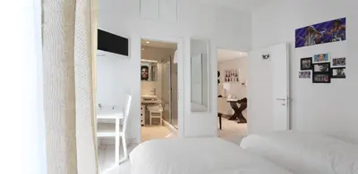 a white bedroom with two beds and a desk at Big Johnny B in Rome