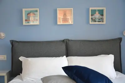 a bed with white pillows and a blue wall at Vatican View Experience in Rome