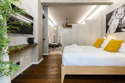 a bedroom with a bed and a table and a kitchen at New Modern in Trastevere with Garden in Rome