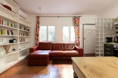 a living room with a brown leather couch and bookshelves at Elegant apartment in Trastevere in Rome