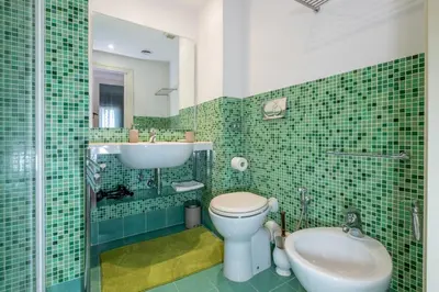a green tiled bathroom with a toilet and a sink at Trevi Terrace Penthouse in Rome