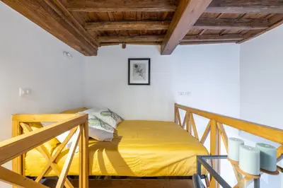 a bedroom with a yellow bed in a room with wooden ceilings at little house in trastevere in Rome
