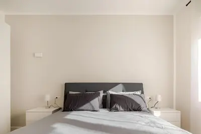 a white bedroom with a large bed with two night stands at Roma Essence Vaticano e Comfort in Rome