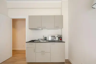 a kitchen with white cabinets and a microwave at Roma Essence Vaticano e Comfort in Rome