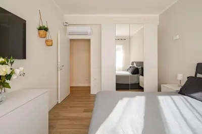 a white bedroom with a bed and a mirror at Roma Essence Vaticano e Comfort in Rome