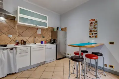 a kitchen with white cabinets and a table and stools at Casa Coronari in Rome