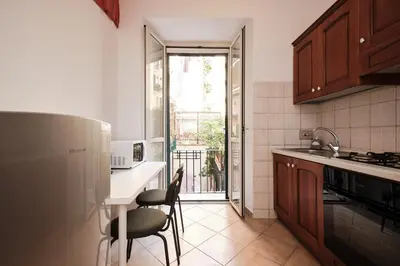 a kitchen with a refrigerator and a table and chairs at Colosseum 3 rooms & 4 bathrooms with garden in Rome