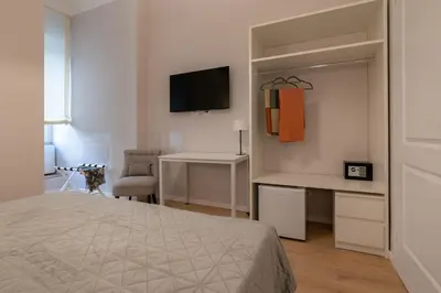 a bedroom with a bed and a desk and a television at Residenza Lucrezio in Rome