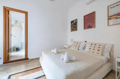 a white bedroom with a large bed and a mirror at Maurice's Apt, hidden gem in Rome for food lovers in Rome