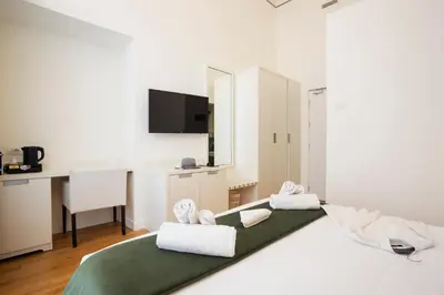 a white bedroom with a desk and a bed with towels at History Suite Essence in Rome
