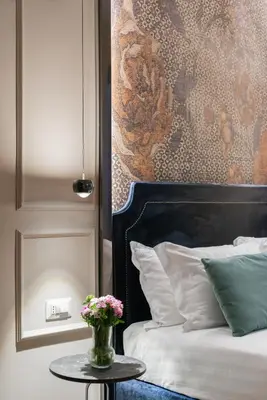 a bedroom with a bed and a table with a vase of flowers at H77 Apartments - Maison D'Art Collection in Rome