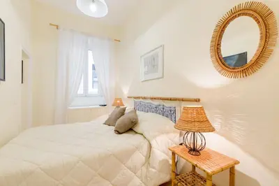 a white bedroom with a bed and a mirror at Central and Historic Rione near Colosseo in Rome
