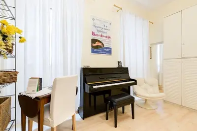a piano in a living room with a desk and a chair at Central and Historic Rione near Colosseo in Rome