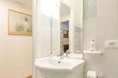 a white bathroom with a sink and a mirror at Central and Historic Rione near Colosseo in Rome