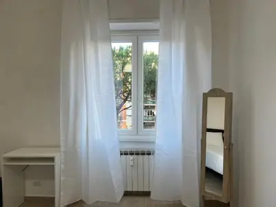 a room with a window with white curtains and a mirror at Dandon Home in Rome