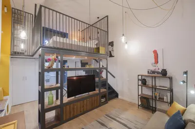 a living room with a tv and a staircase at Design and Colorful Loft near Villa Pamphili in Rome