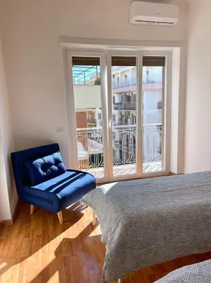 a bedroom with a blue chair and a window at Roma Lux Apartment Lorenzo in Rome