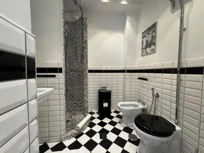 a bathroom with a black toilet and a checkered floor at Room 55 Testaccio in Rome