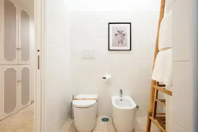 a white bathroom with a toilet and a ladder at BruSilva al Colosseo in Rome