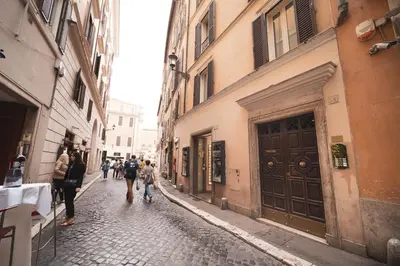 a group of people walking down a narrow street at Trevi Fountain by BuddyRent in Rome