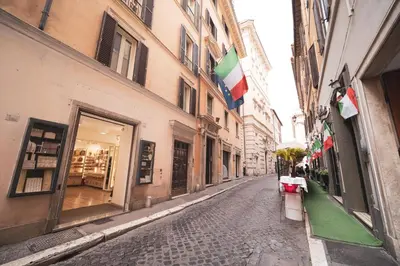 an empty street in a city with flags on buildings at Trevi Fountain by BuddyRent in Rome