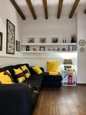 a living room with a black couch and yellow pillows at Casetta del Bassotto in Rome