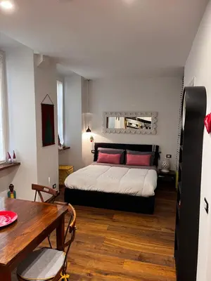 a bedroom with a bed with red pillows and a table at Casetta del Bassotto in Rome