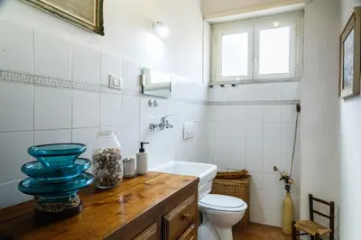 a bathroom with a toilet and a blue vase on a counter at Olimpico Apartment in Rome