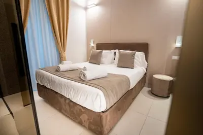 a bedroom with a bed with white sheets and pillows at Cicerone's Luxury Suites in Rome