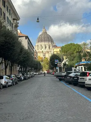 a street with a building in the background with cars parked at Casa Città del Vaticano in Rome