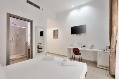 a white bedroom with two beds and a red chair at Merulana 43 - Guest House in Rome