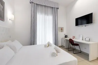 a white bedroom with a bed and a desk and a television at Merulana 43 - Guest House in Rome
