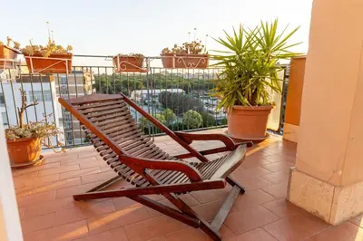 a rocking chair sitting on a balcony with plants at Eur-motagnola attico 2bedr apt 280 terrace view in Rome