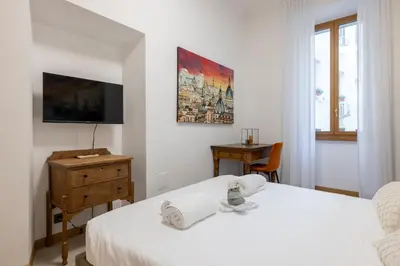a white bedroom with a bed and a tv at Quattro Fontane 2P - B&D Apartments in Rome