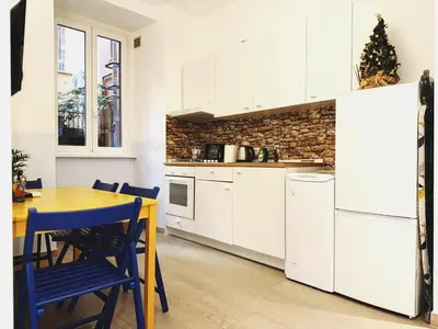 a kitchen with white cabinets and a table and blue chairs at Scala Santa Home in Rome