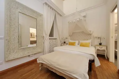 a white bedroom with two beds and a mirror at Vicolo Savelli Luxury Suites in Rome