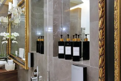 a bathroom with a mirror and a bunch of bottles at Vicolo Savelli Luxury Suites in Rome