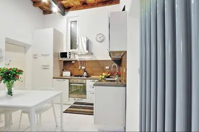 a kitchen with white cabinets and a white table at Campo de fiori charm apartment in Rome