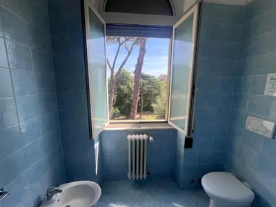 a bathroom with a window and a toilet and a sink at Green Park San Pancrazio in Rome